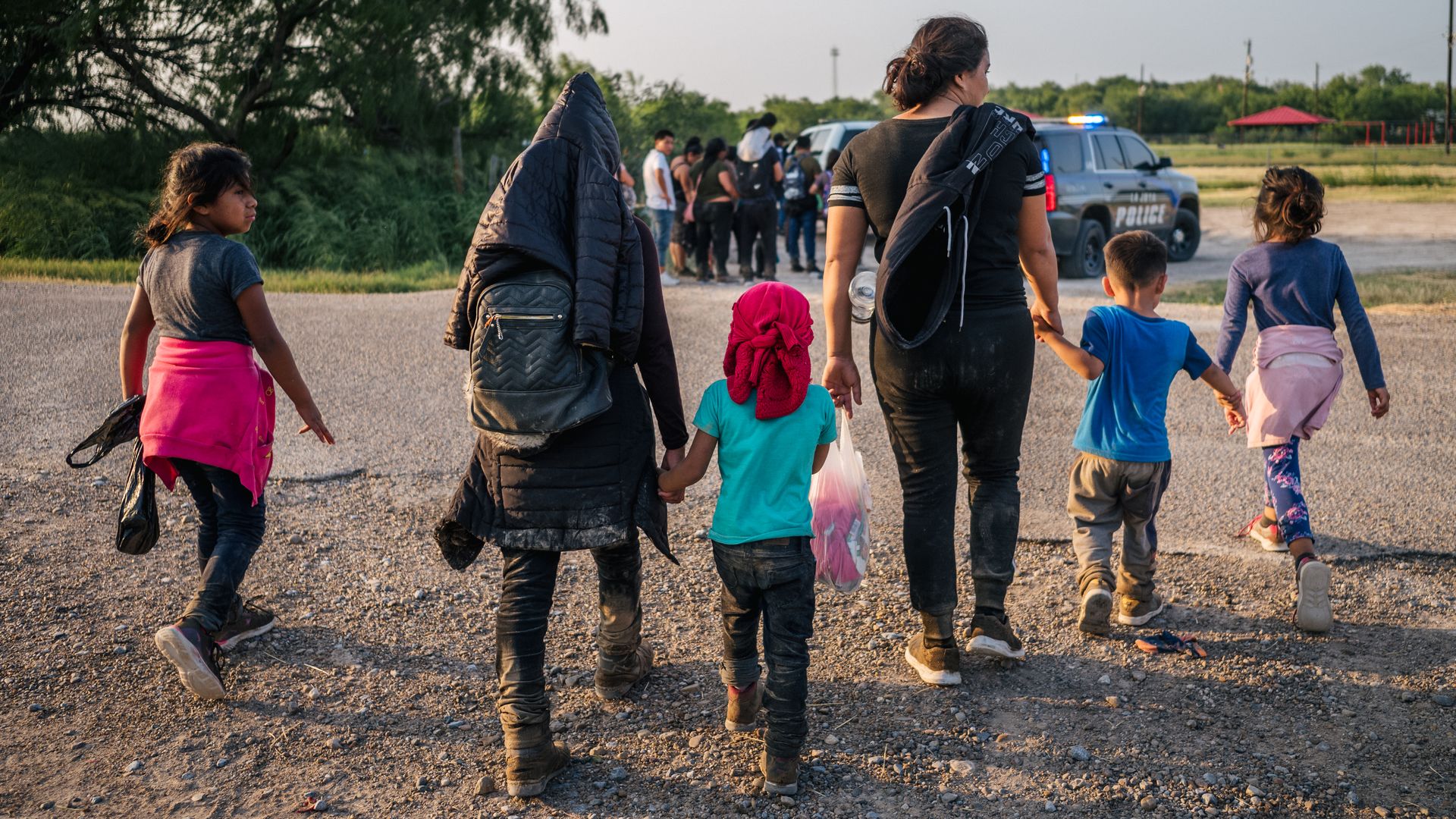 Migrants are seen walking toward law enforcement officers after crossing the U.S.-Mexico border.