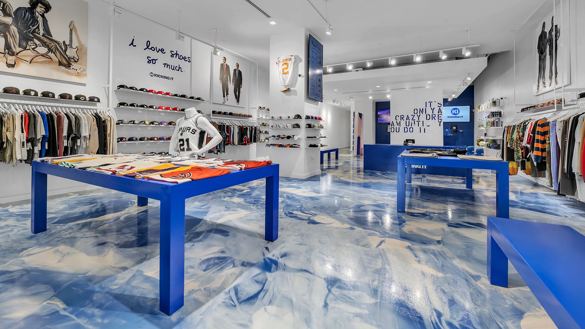 A store with racks of clothing, shoes on shelves lining the wall and blue accents. 