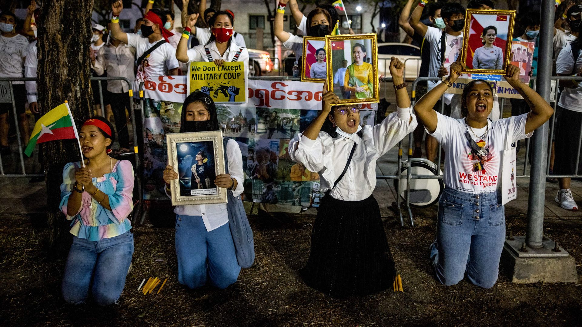 Picture of Myanmar migrants on their knees holding framed pictures of political prisoners and asking for them to be released