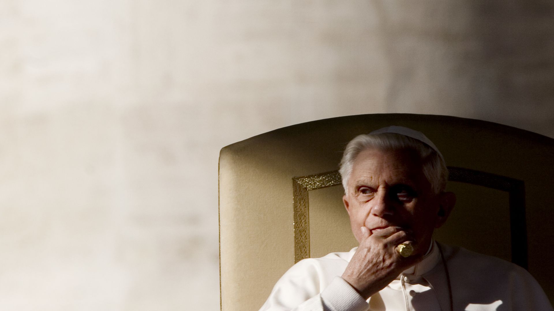 former pope benedict xvi sits in chair with head resting on hand