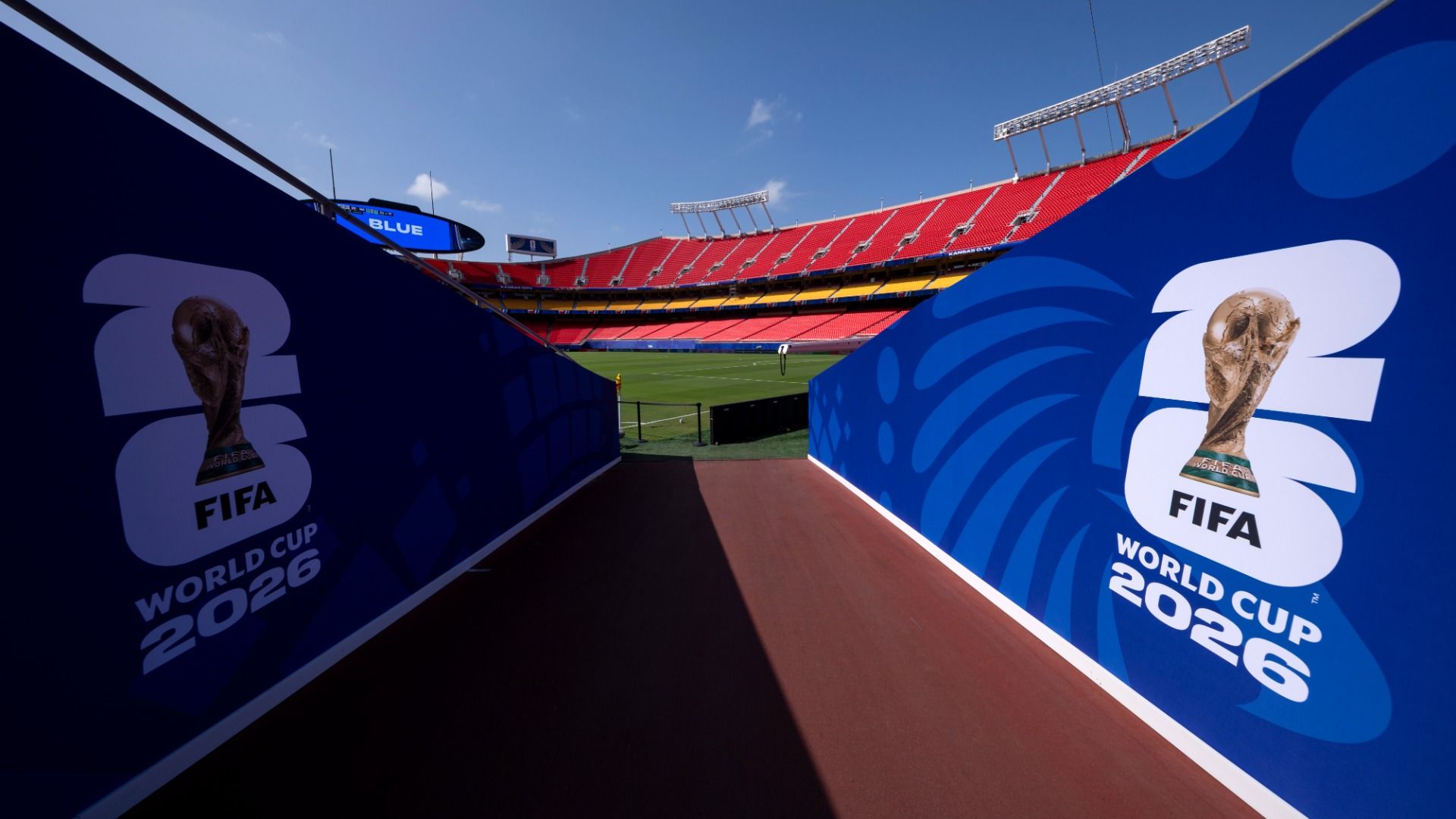 A general view of FIFA World Cup 2026 signage at Kansas City Stadium looking out from a tunnel onto the field with red stands rising in the background.