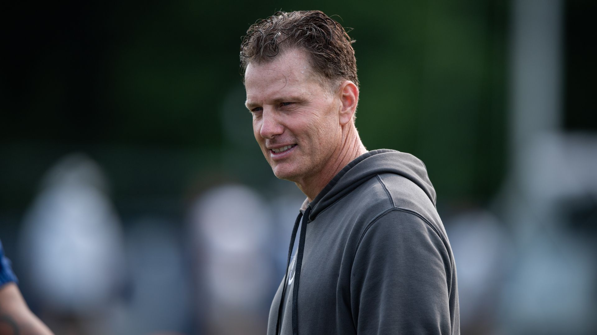 Photo of a man on sidelines coaching football. 