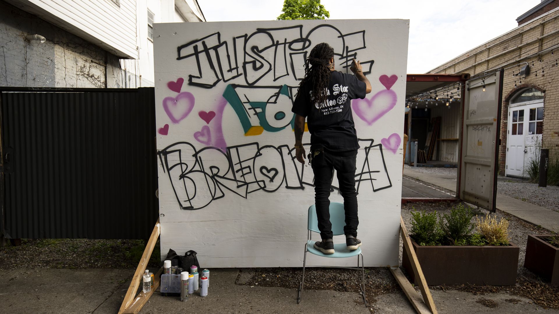 A man spray paints a sign that reads "Justice for Breonna" as Louisville remains in a state of protest