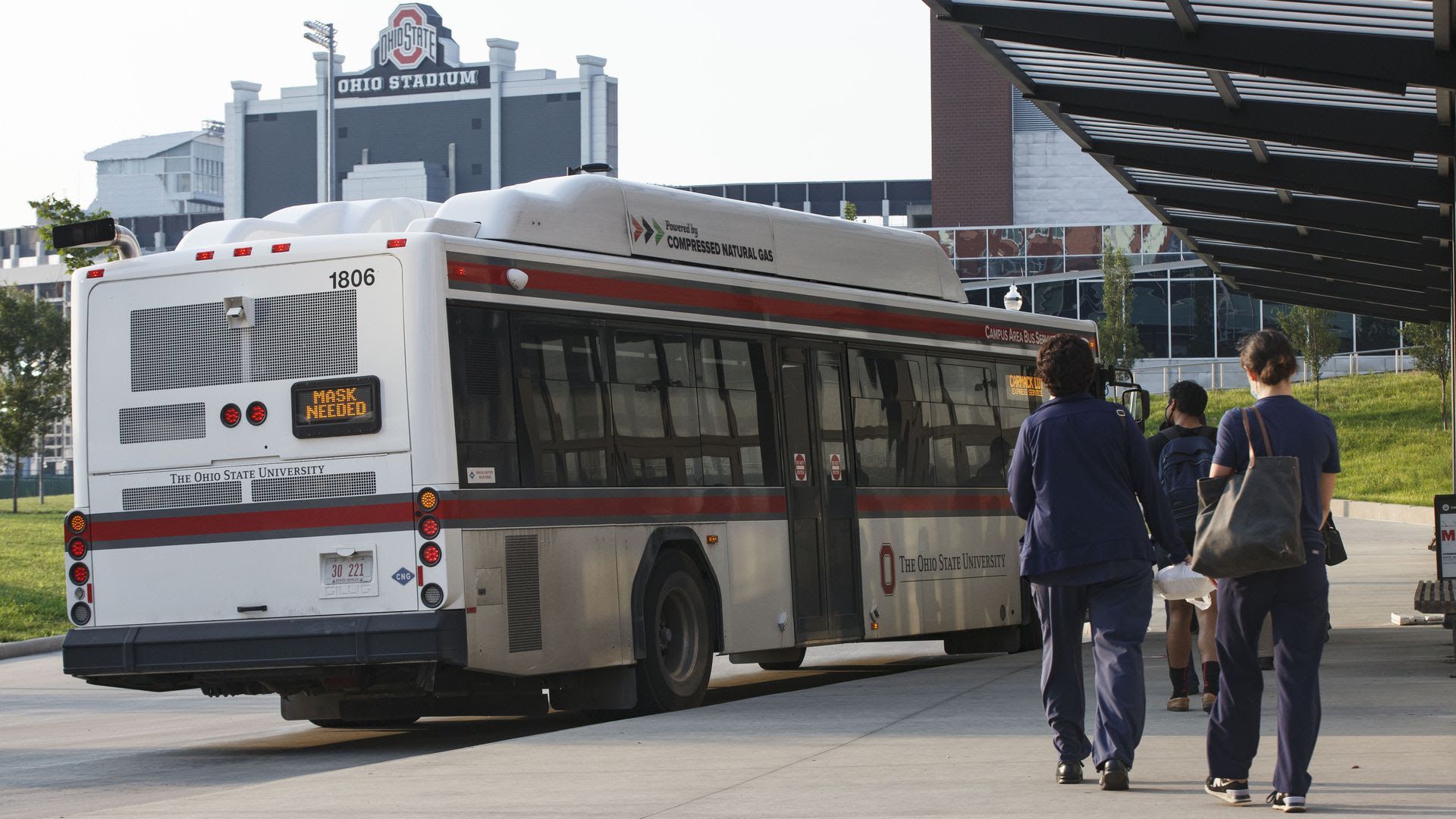 Students and medical workers line up to take a bus on the Ohio State University campus.