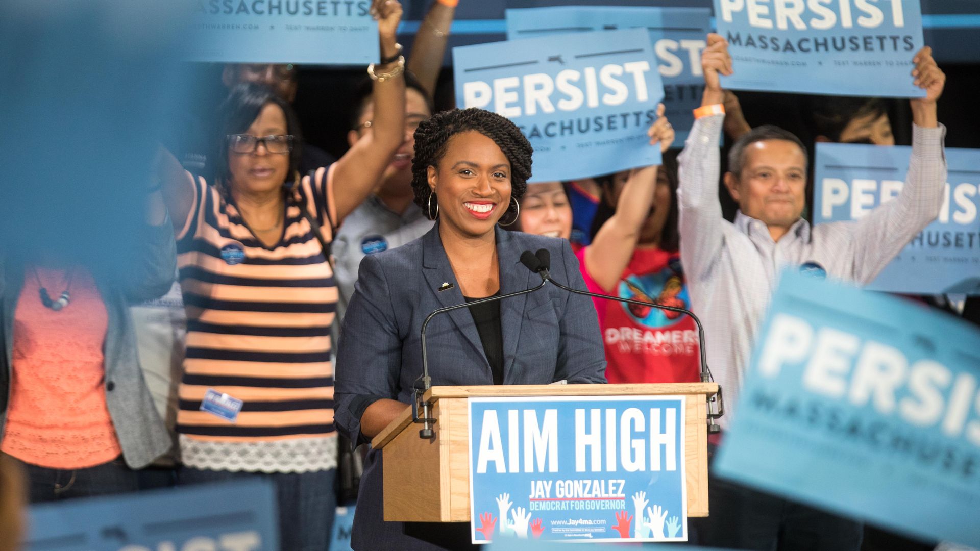 Ayanna Pressley at a campaign rally, surrounded by "Persist" signs.