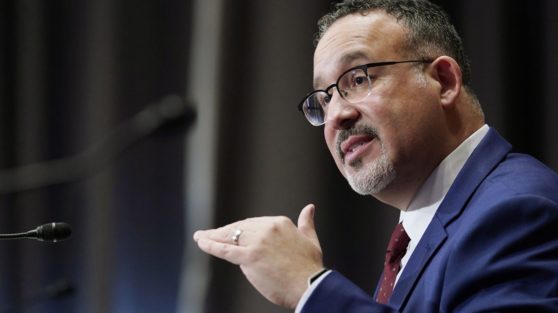 Photo of Miguel Cardona speaking and gesturing with one hand