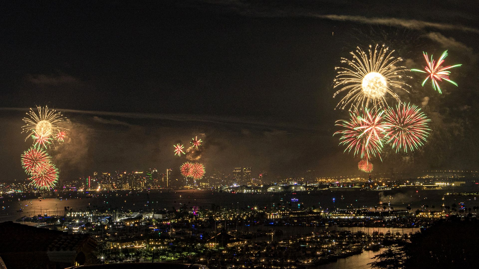 Colorful fireworks explode in the sky from three different launch points over San Diego.