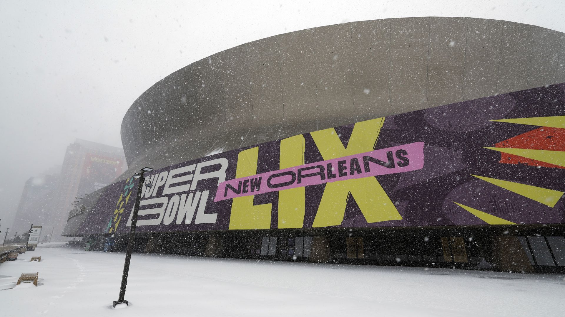 The Superdome is seen in the snow. A sign says Super Bowl LIX New Orleans.