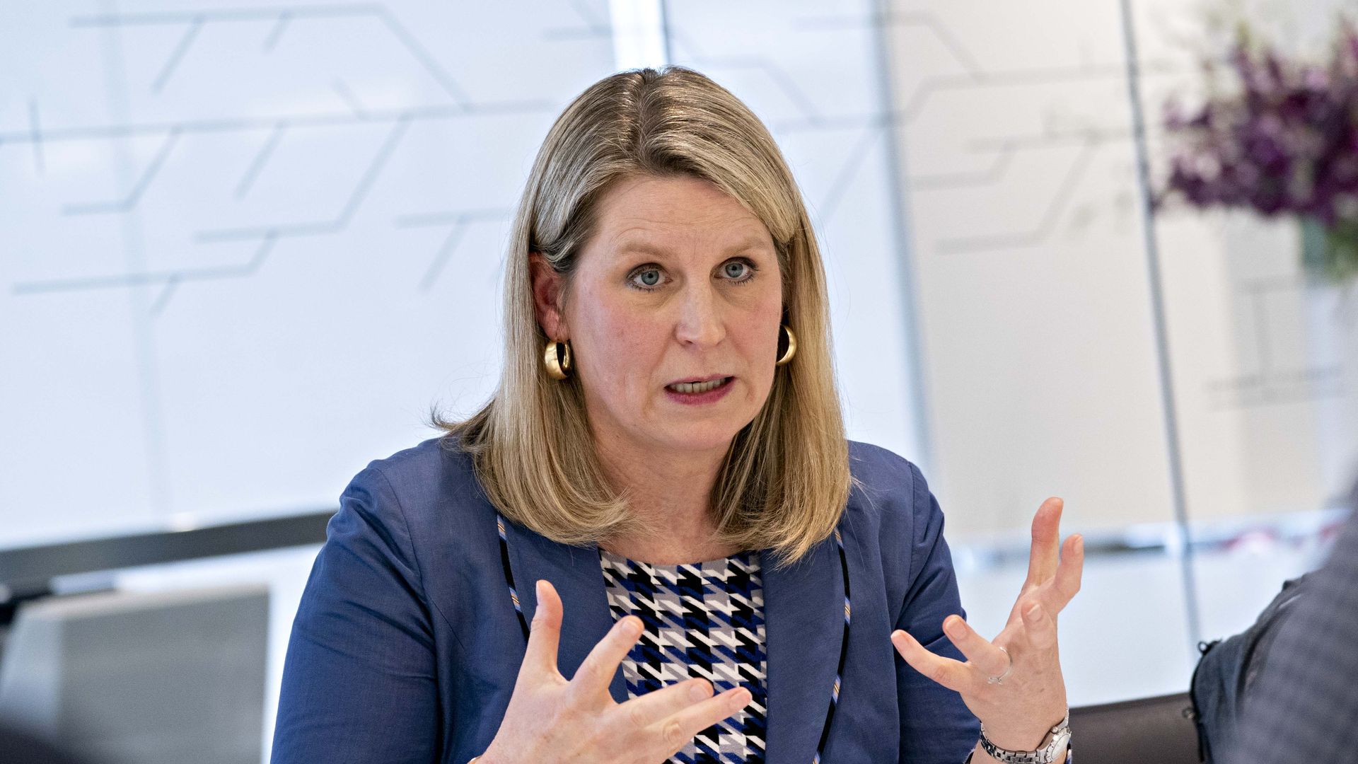 Liz Shuler gesticulates with her hands in a blue suit.