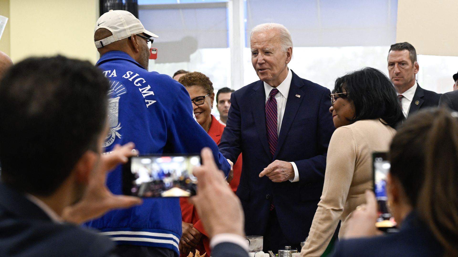 President Biden, wearing a dark blue suit, white shirt and maroon tie.