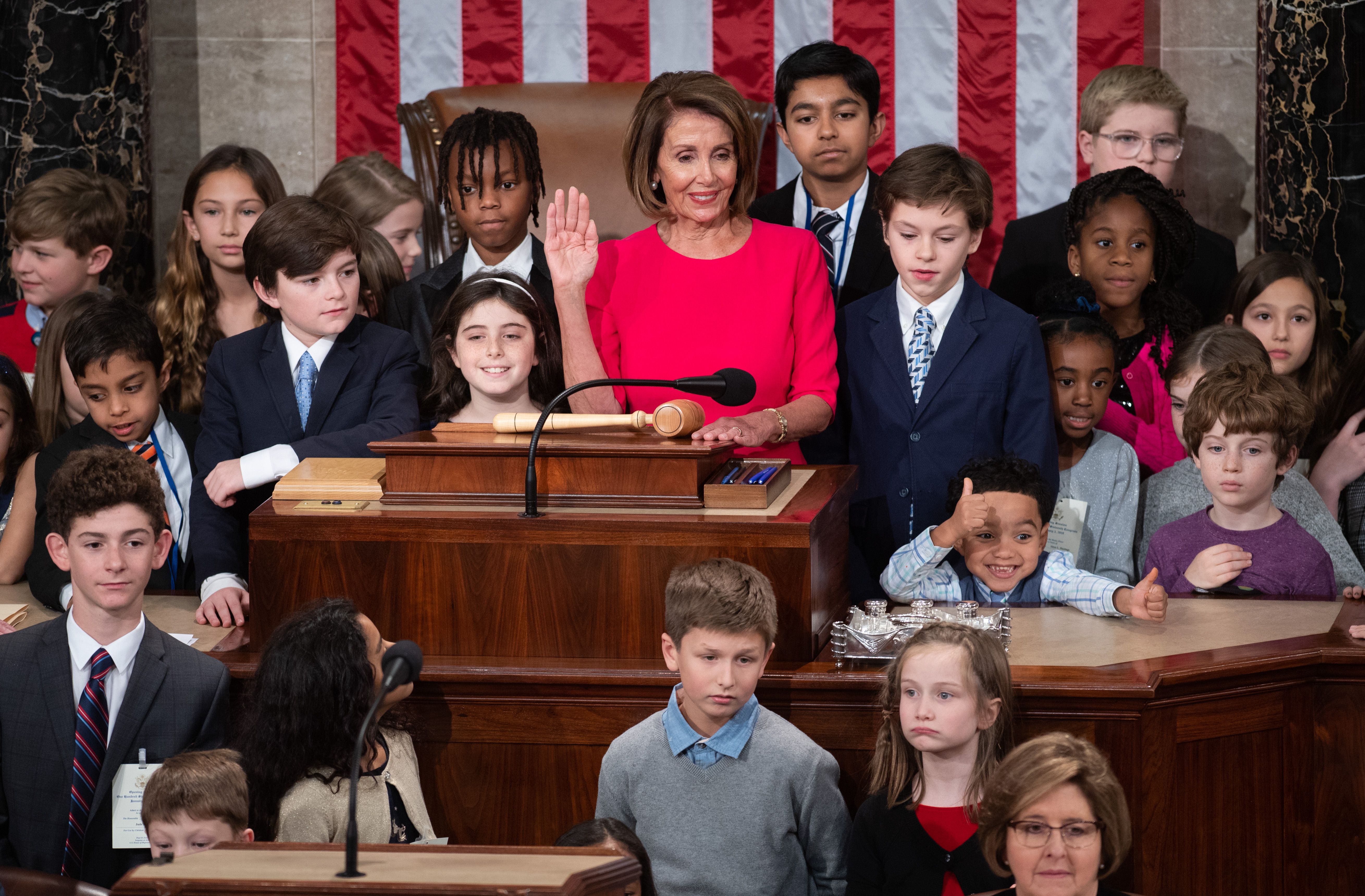 Nancy Pelosi surrounded by children at the podium.