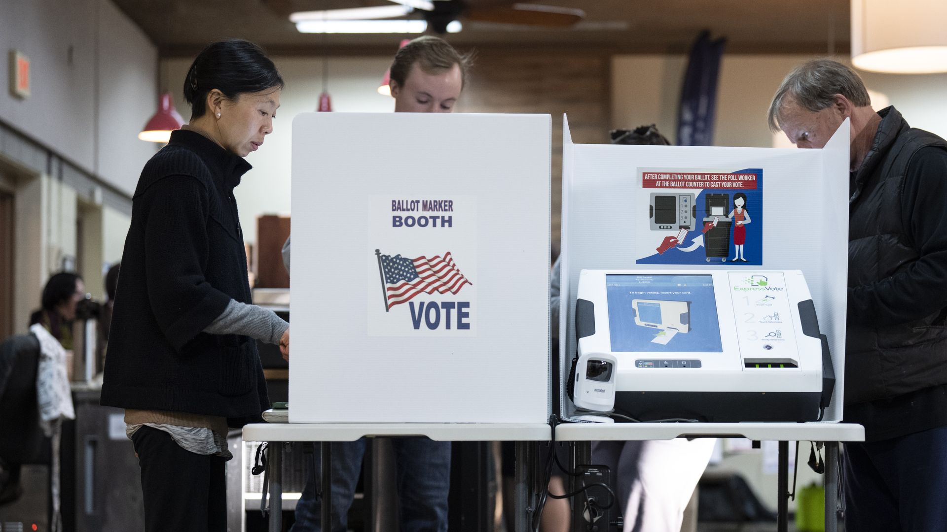 Voters stand behind white dividers that block others from viewing their ballot