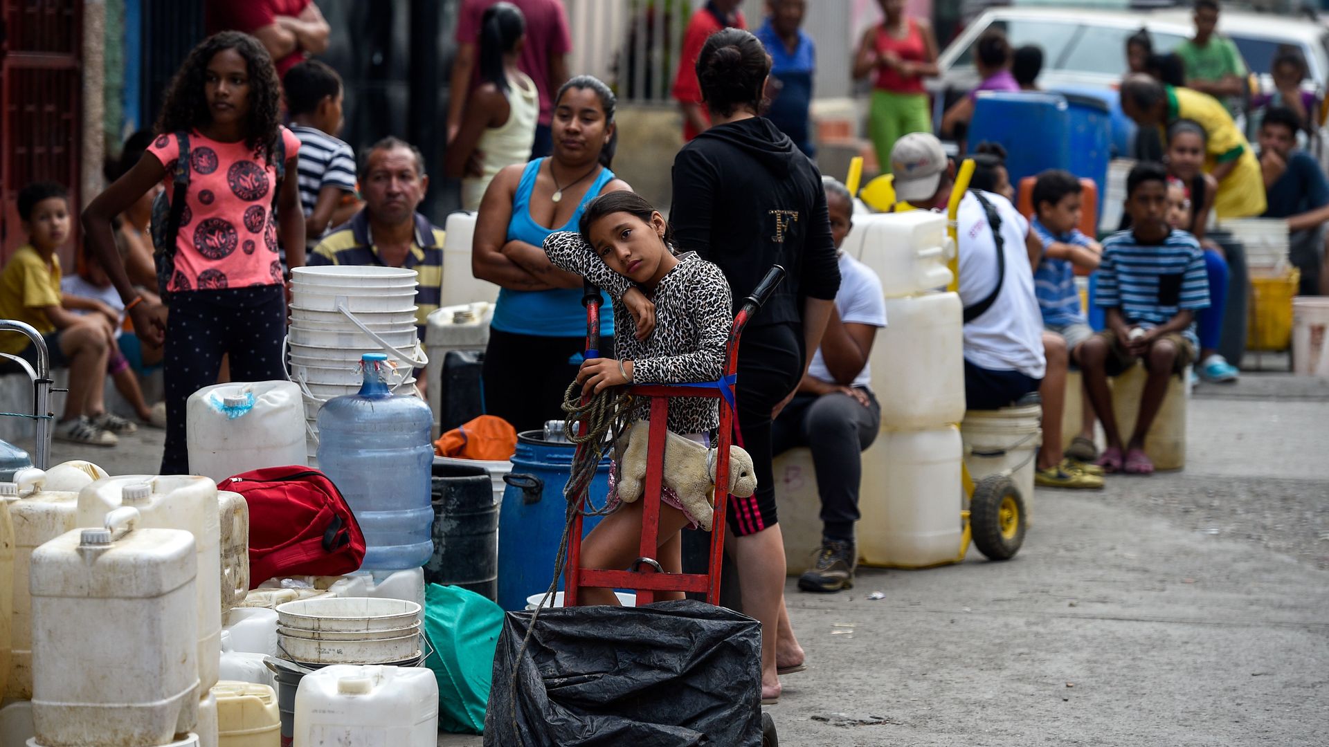 People line up with cans and tanks to collect water, at Petare neighborhood in Caracas
