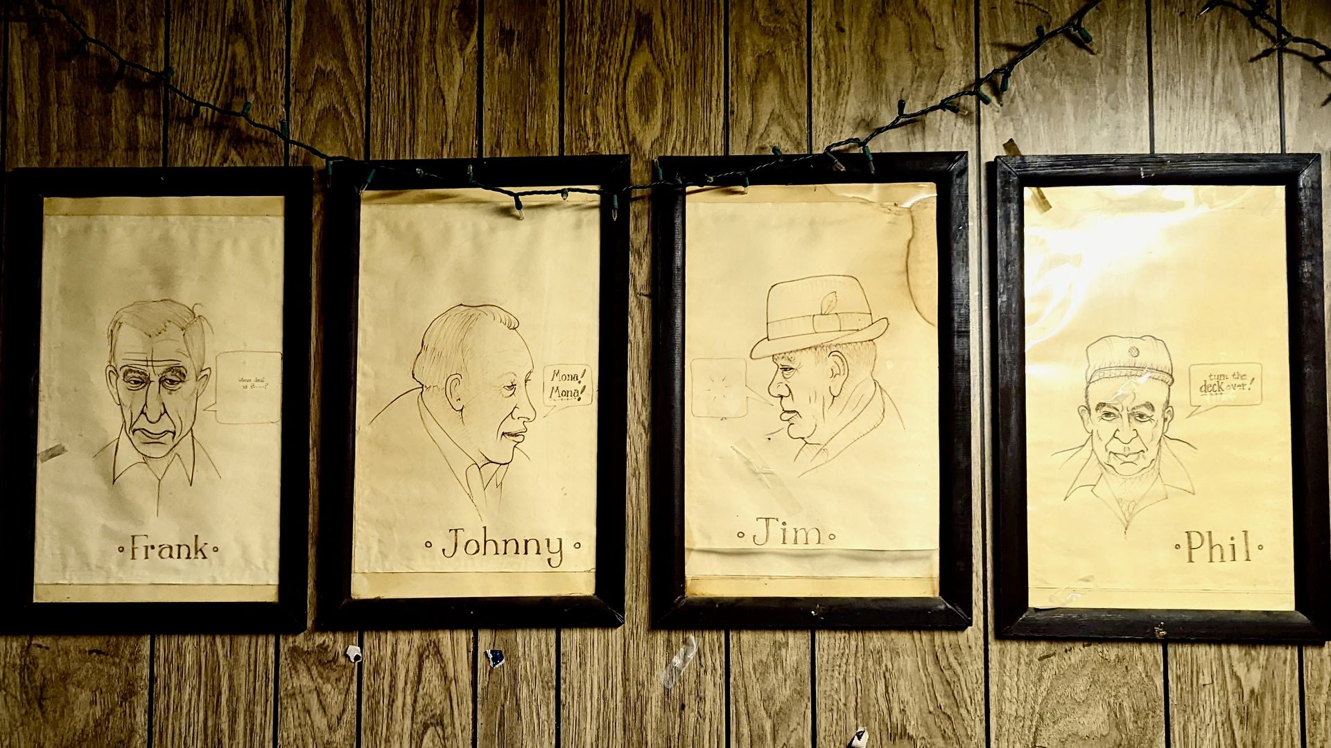 Drawn portraits of men, labeled with their names: Frank, Johnny, Jim and Phil. Hanging on a wood-paneled wall.
