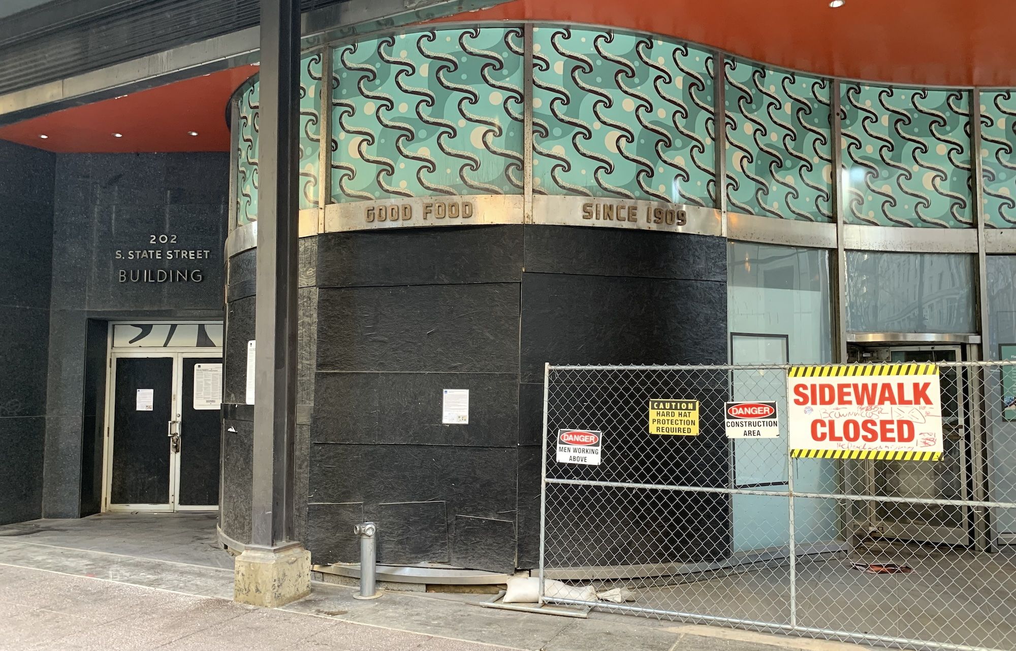 Fence with sidewalk closed sign in front of building.