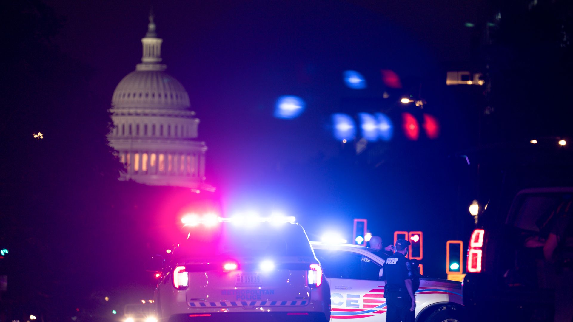 A police car with its red and blue lights on and the U.S. Capitol in the background.