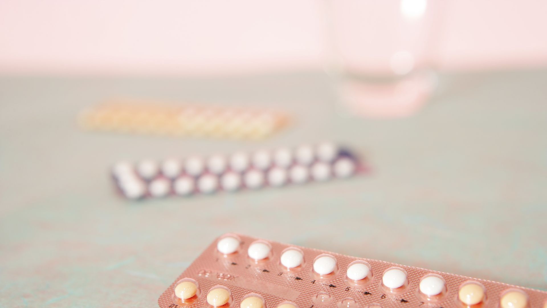 Image of three birth control pill packs in pastel colors.