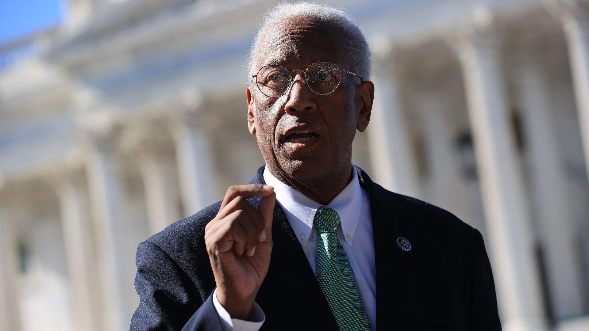 Rep. Donald McEachin, wearing a blue suit jacket, white shirt and green tie, speaks in front of the U.S. Capitol.
