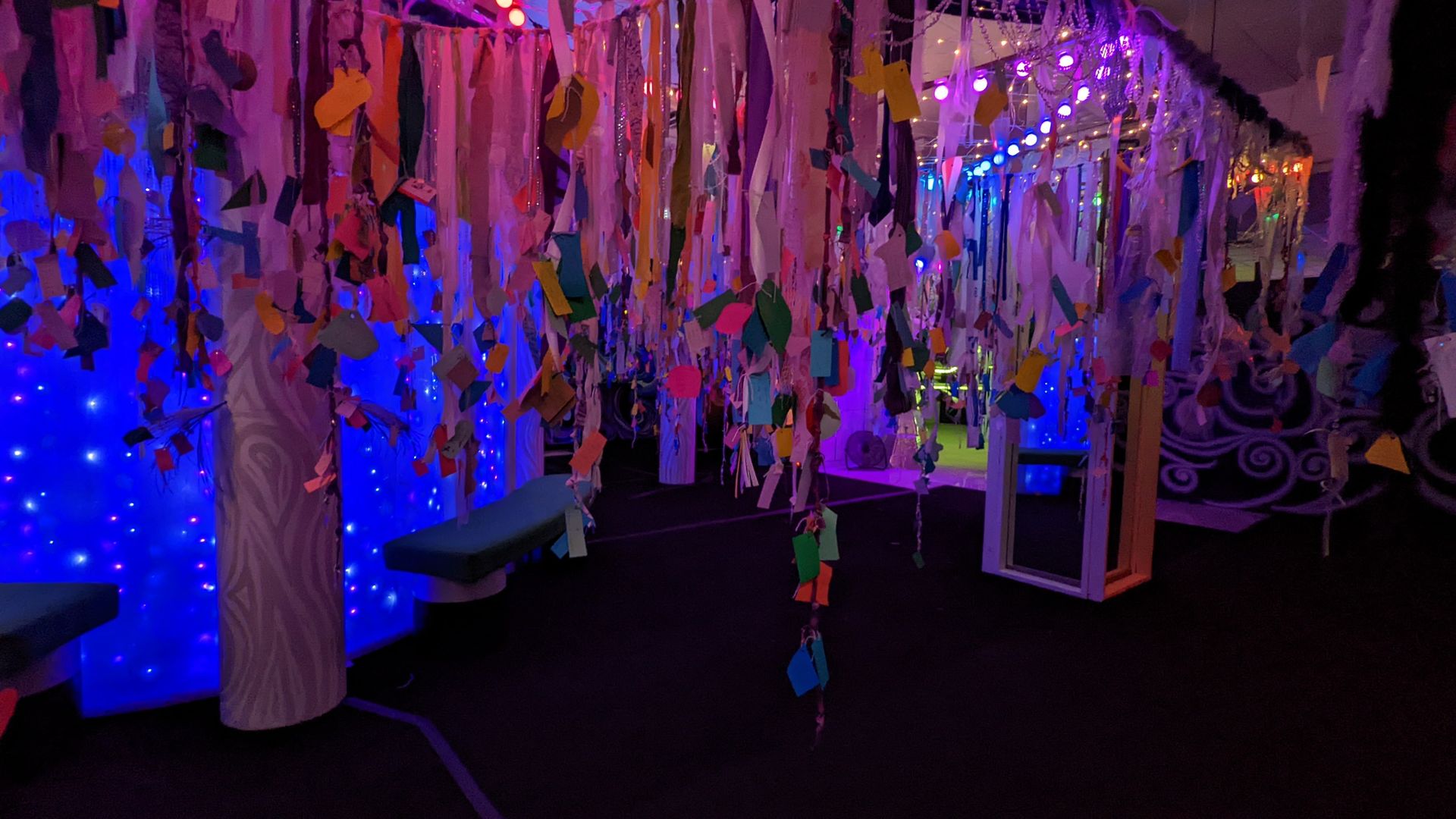 Colored pieces of paper hang from a glowing tree sculpture.