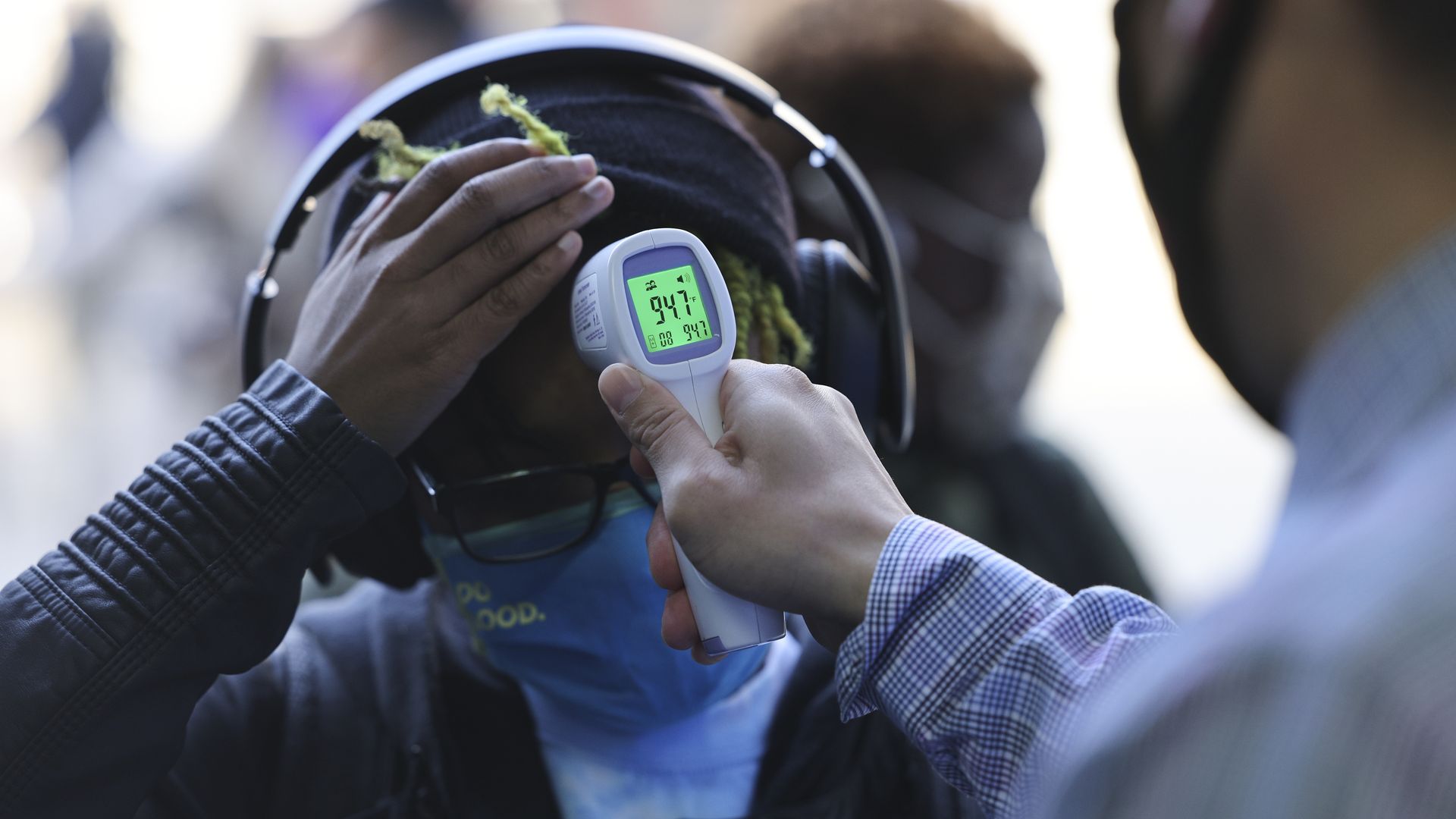 A student has their temperature taken while entering a New York City public high school on  March 22, 2021.
