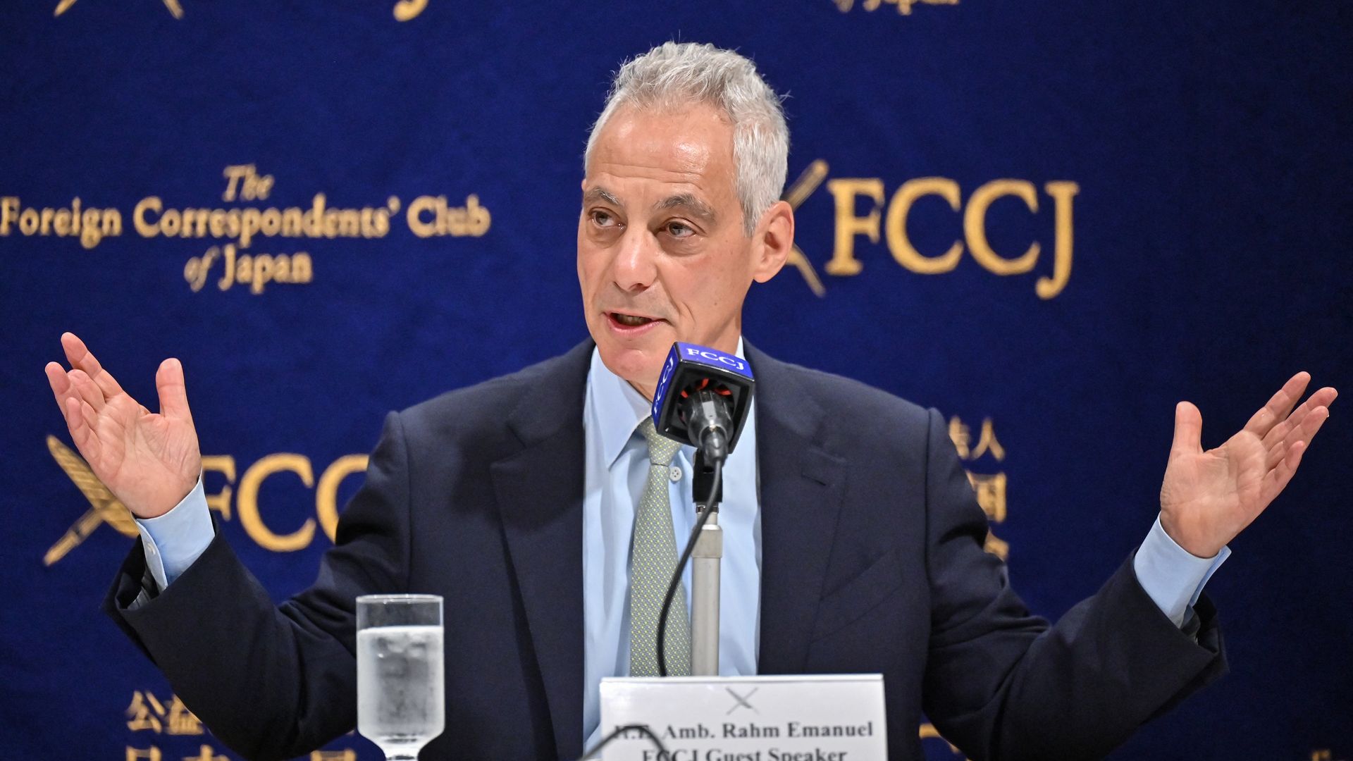 Photo of a man with his hands outstretched behind a microphone. 