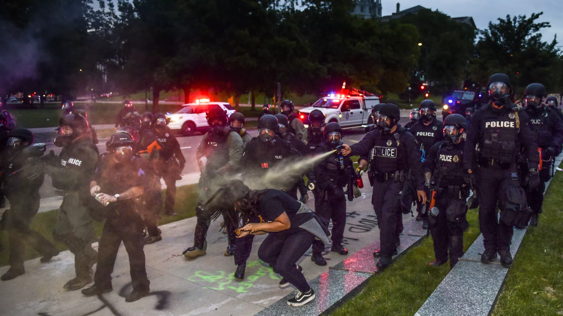 Police officers pepper spray a woman next to the Colorado State Capitol as protests against the death of George Floyd continue for a third night on May 30, 2020 in Denver.