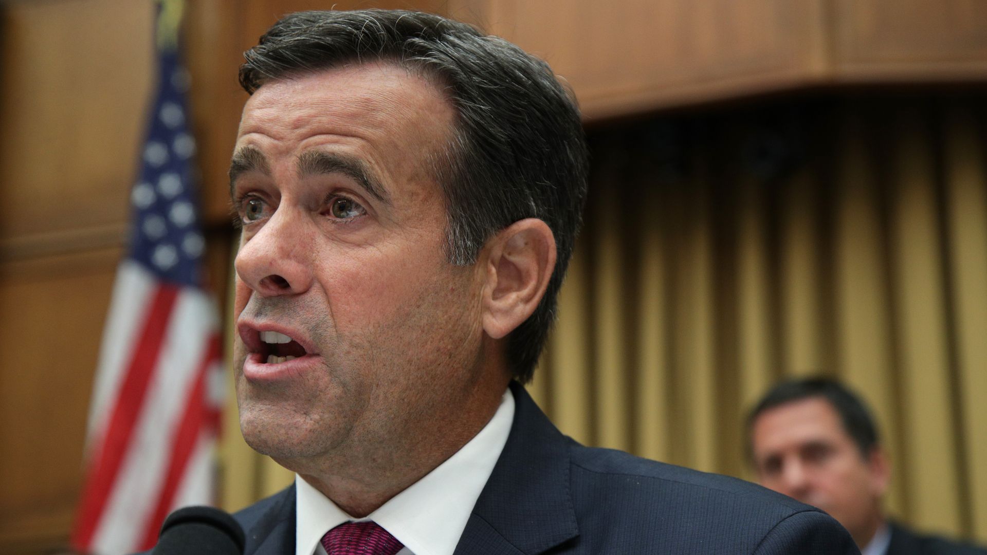 This image shows Ratcliffe speaking while wearing a suit at a hearing.