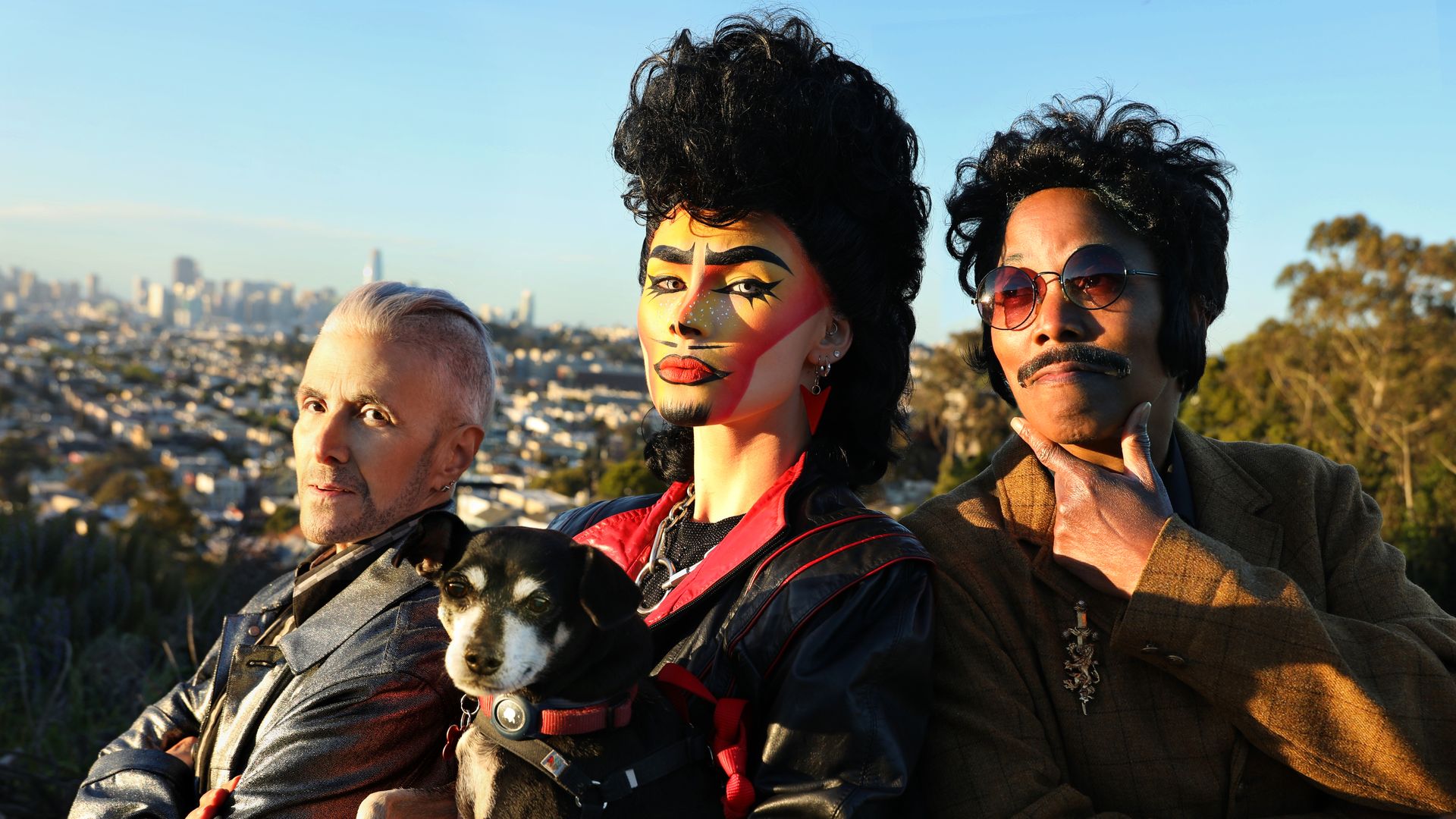 people in drag with a dog with SF in background