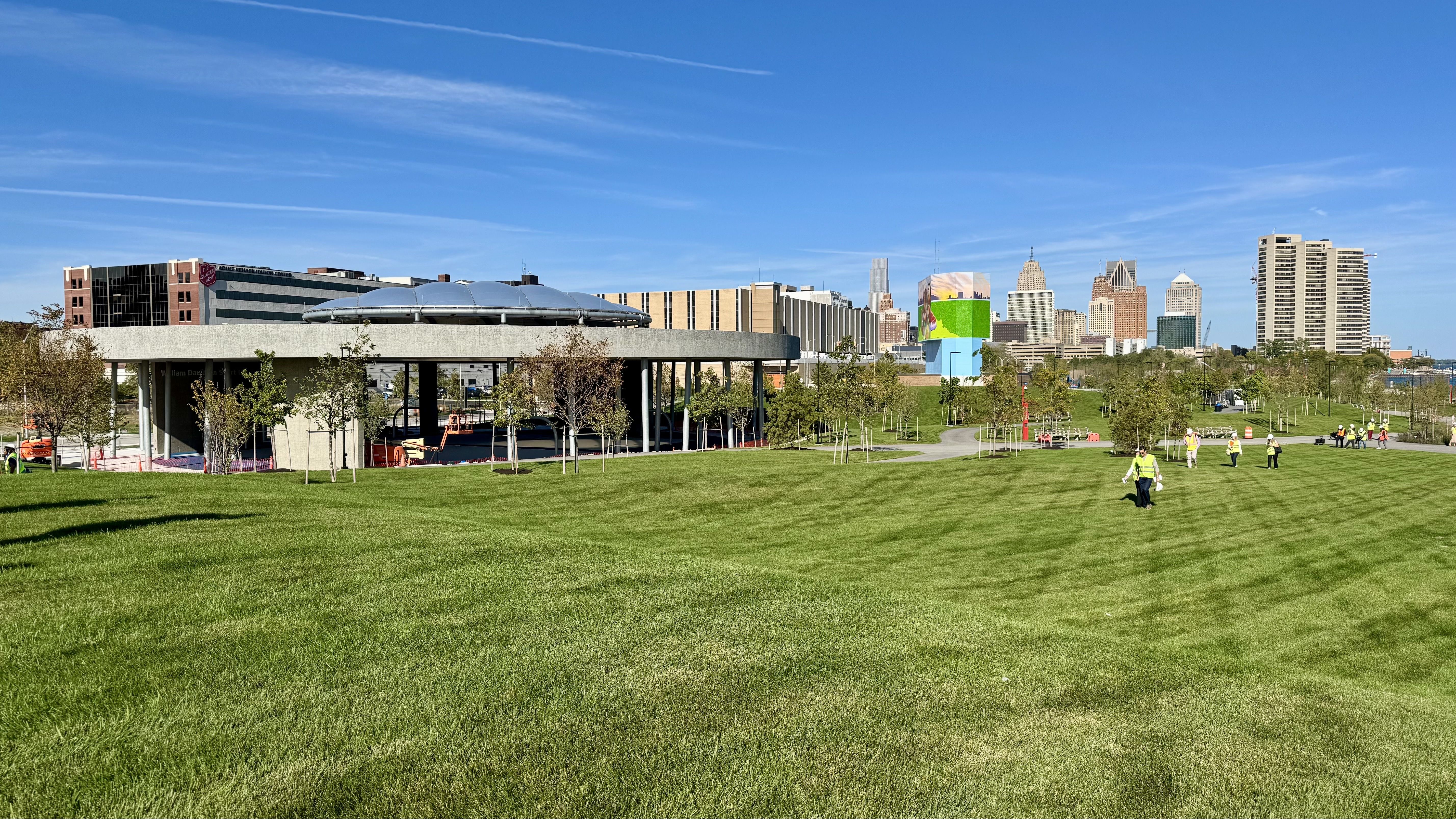 A view shows a giant grassy area with the skyline in the background. There's also a giant sports pavilion