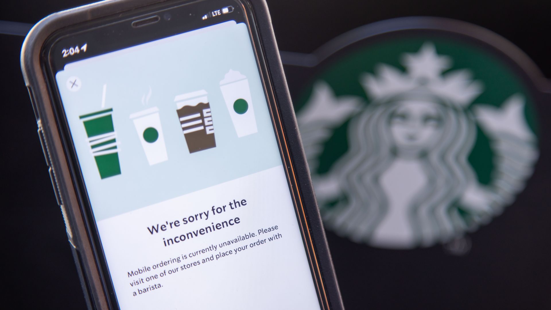 Mobile phone with Starbucks message that says "We're sorry for the inconvenience" next to Starbucks logo