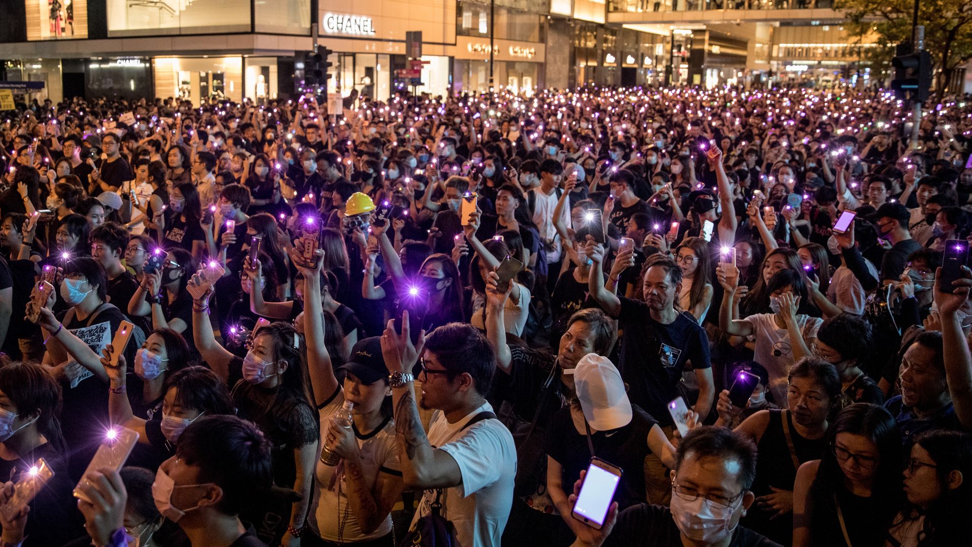 Protesters wave their phones in the air during a #MeToo rally against police sexual harassment on August 30