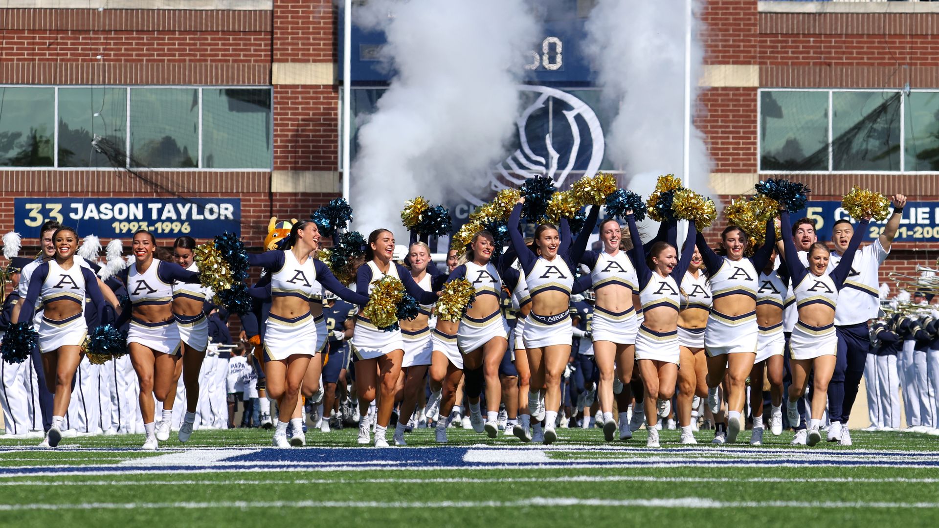Akron Zips cheerleaders run onto the football field.
