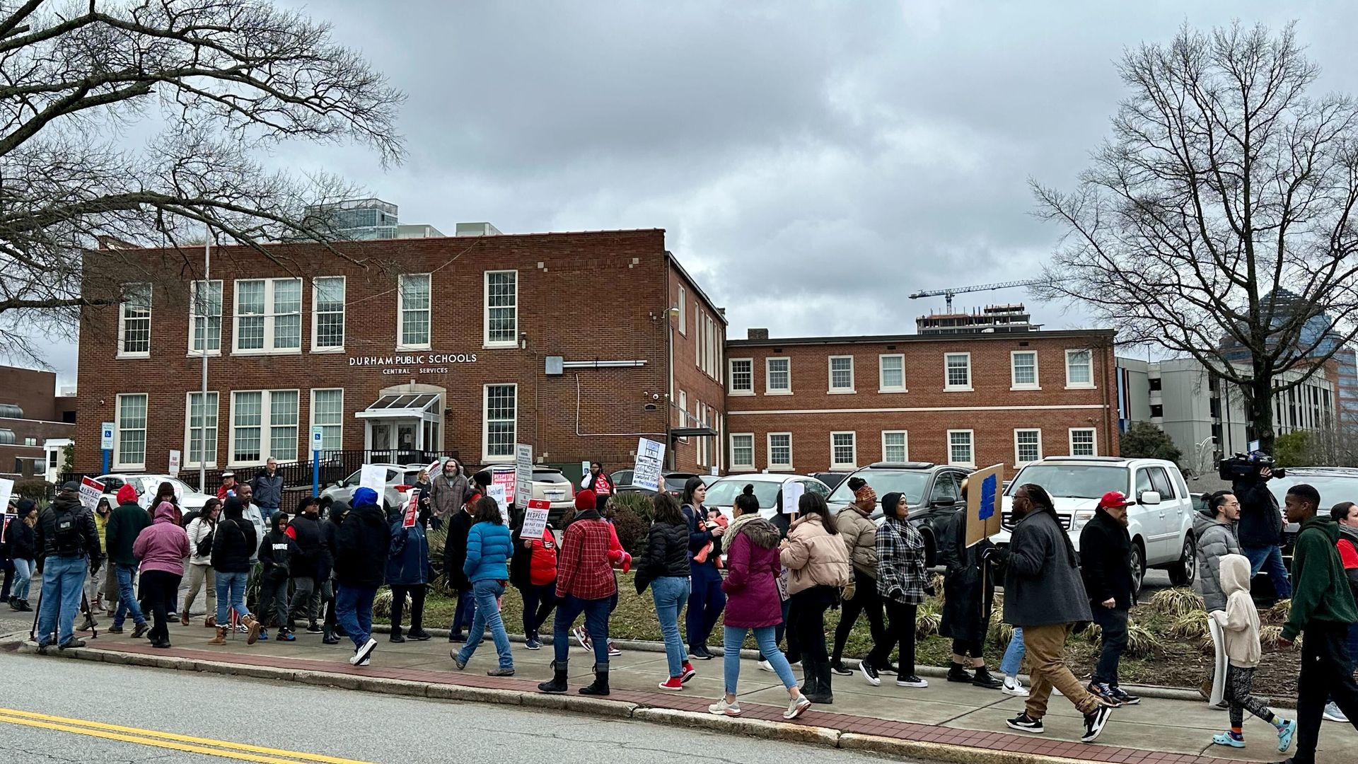 Dozens of protesters marching with signs in front of the Durham Public Schools administrative building