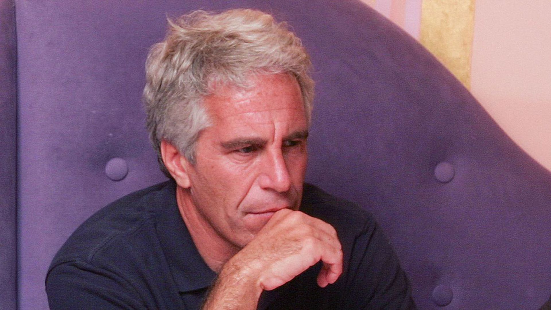 Jeffrey Epstein sits on a sofa.