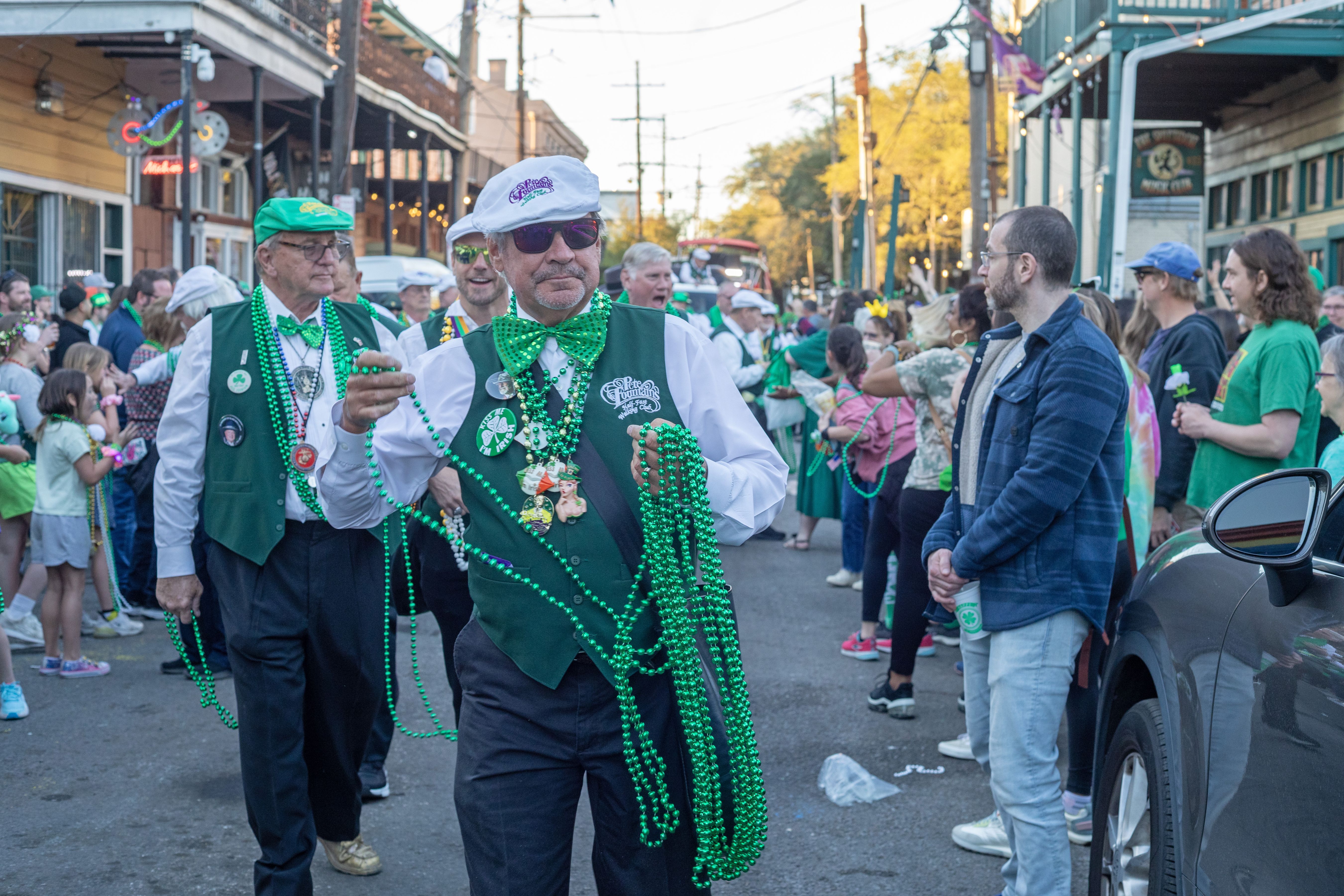 Image shows men in green handing out green beads.