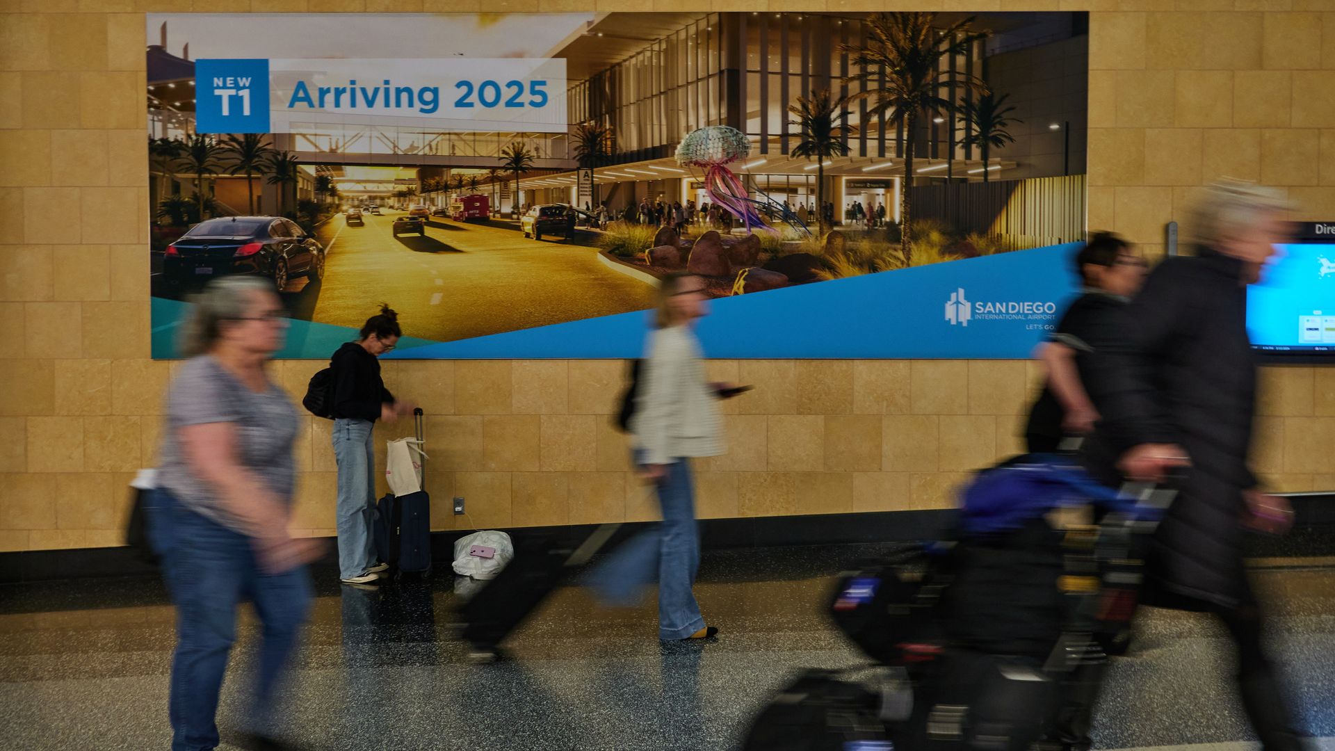 Airport passengers pass a sign advertising the Terminal 1 reconstruction
