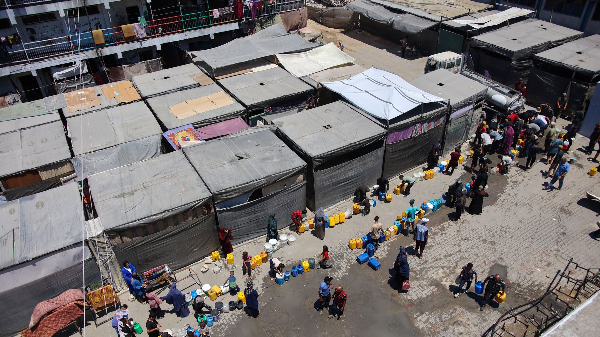 Displaced Palestinians line up to fill containers with water at a UN Relief and Works Agency for Palestine Refugees school.