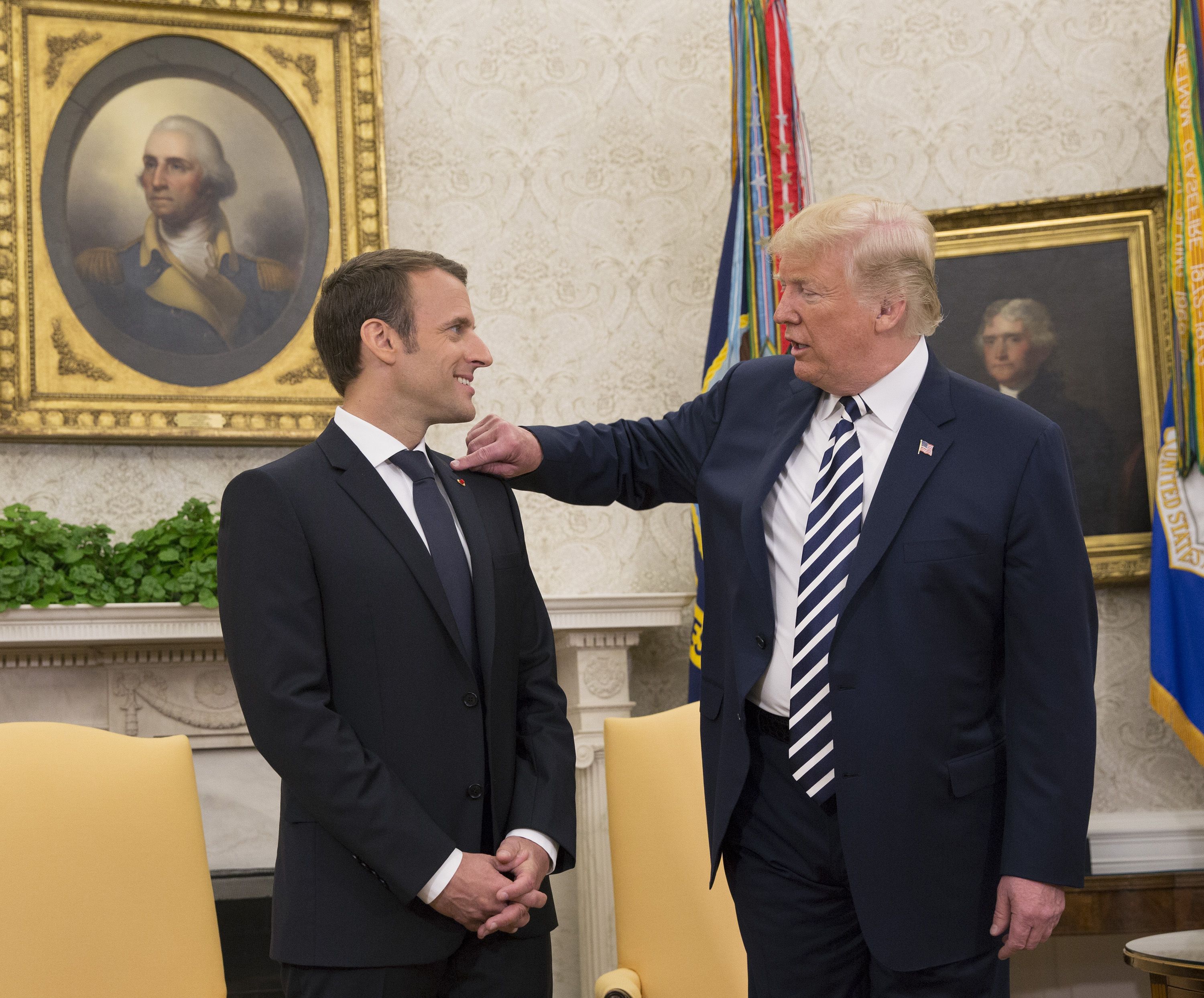 Trump flicks dandruff off Macron's jacket