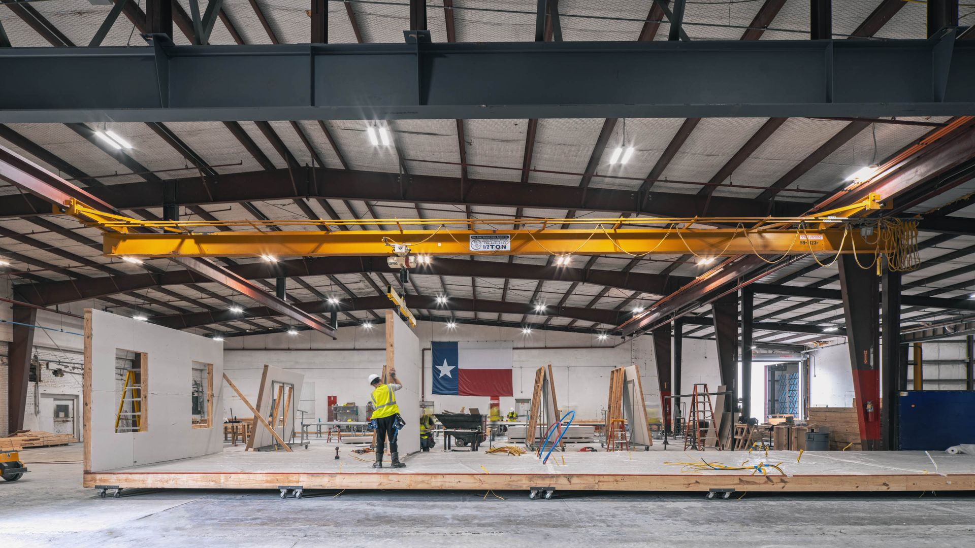 A photo of a factory with a construction worker in the center and a Texas flag in the background.