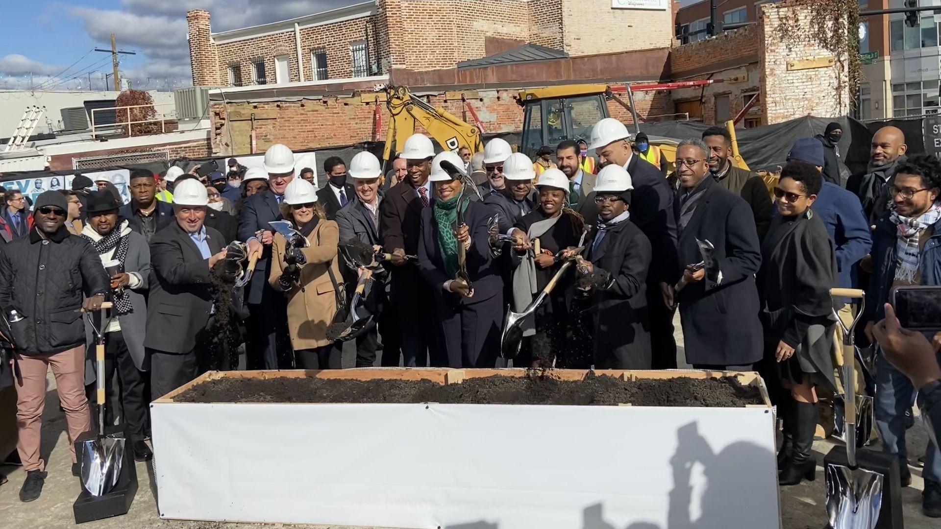 A crowd of D.C. leaders and developers shoveling dirt in a ceremonial groundbreaking.