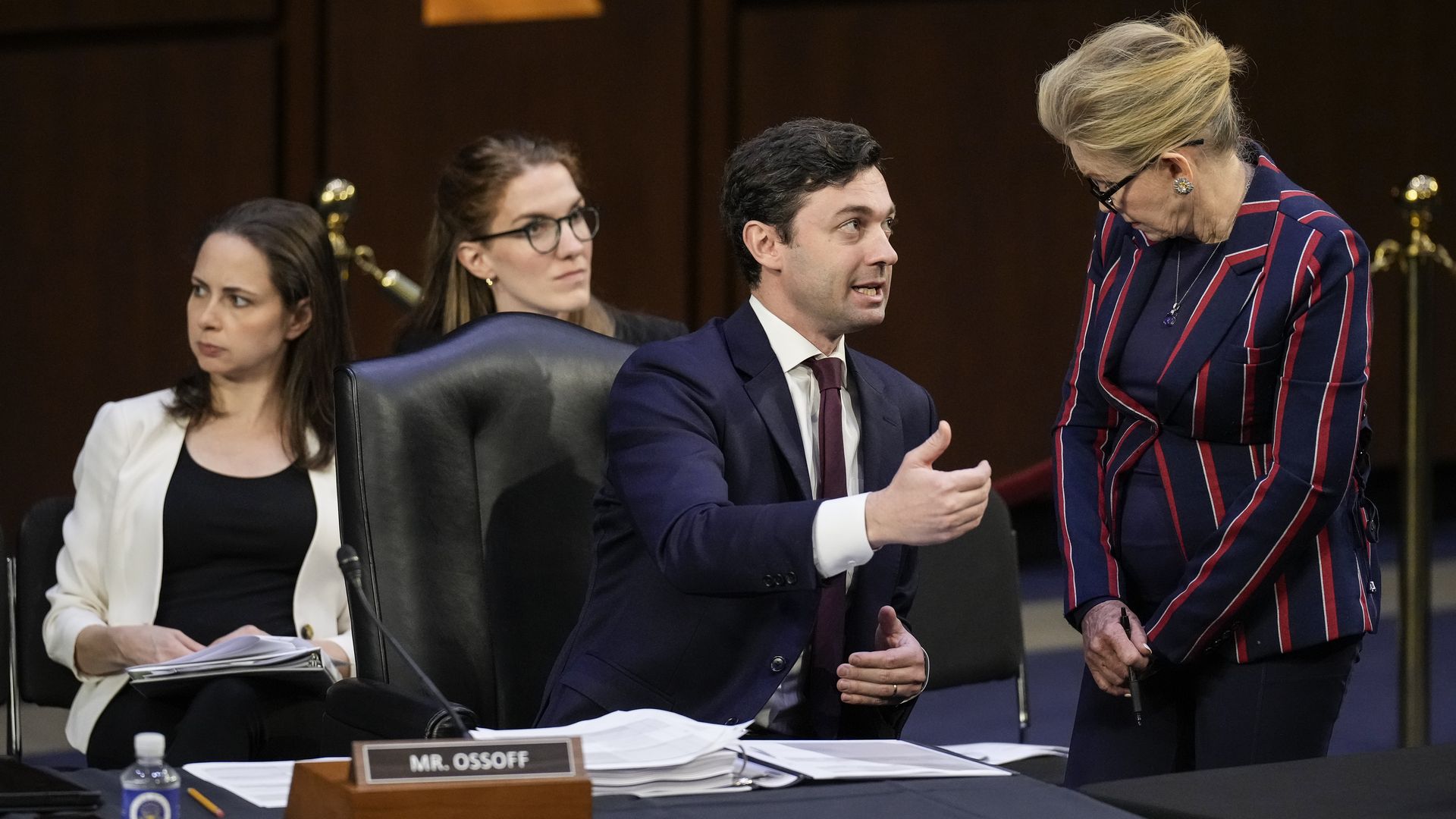 One person seated talks to another person standing during a congressional hearing