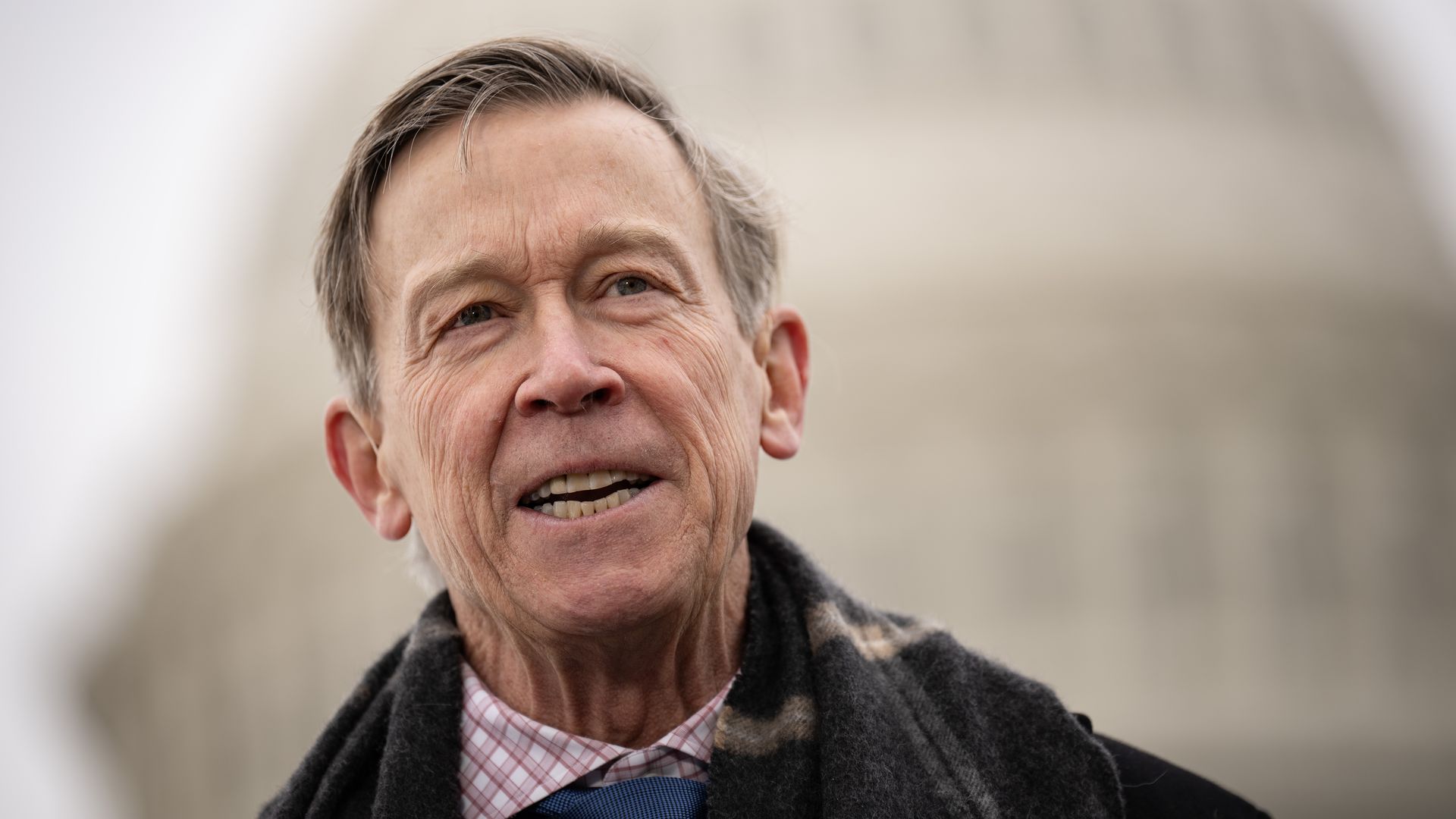 Senator John Hickenlooper stands in front of the Capitol building