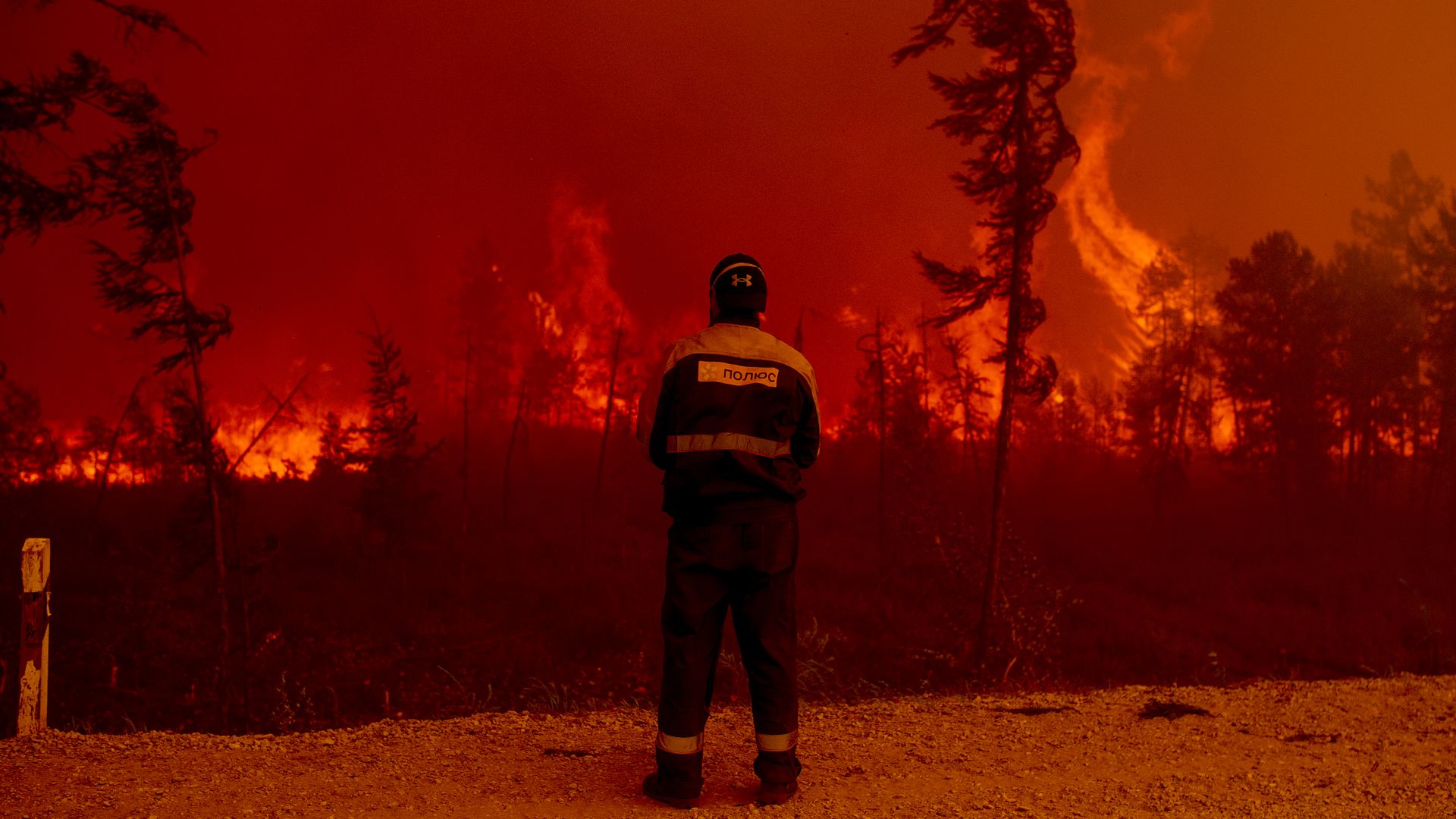 Man standing in front of a burning forest.