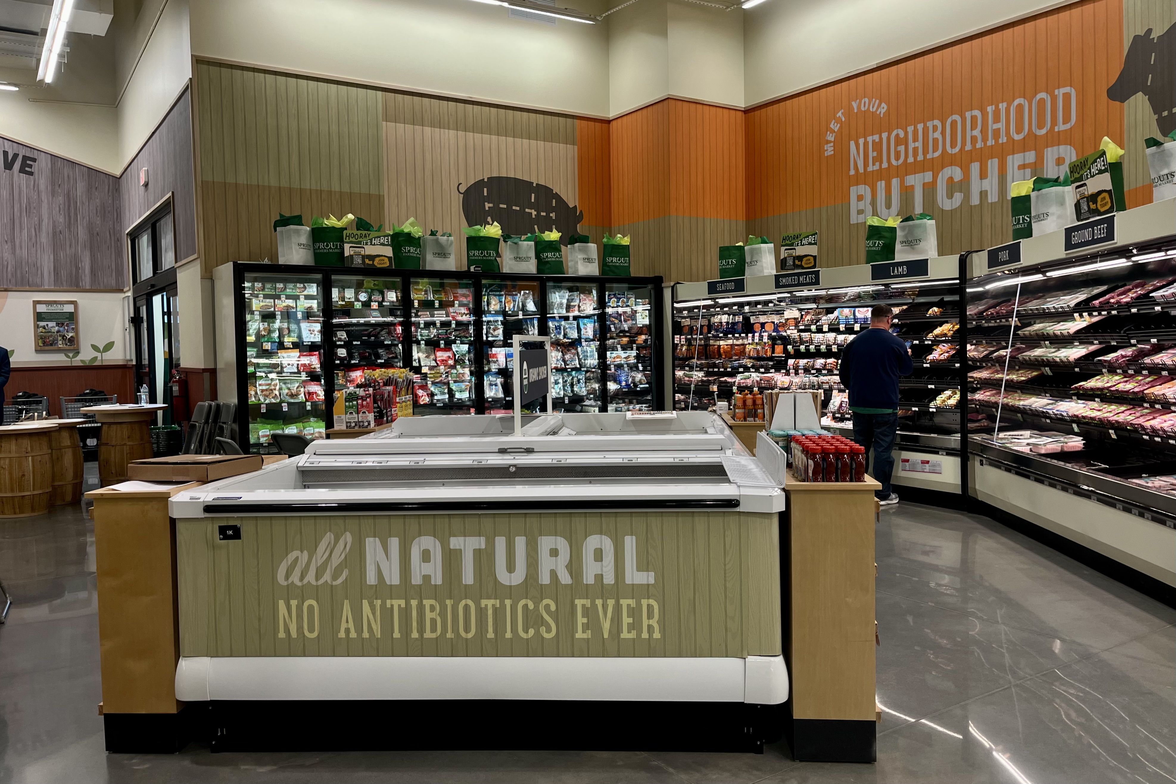 Grocery store butcher section with signs. Shelves stocked with meat.