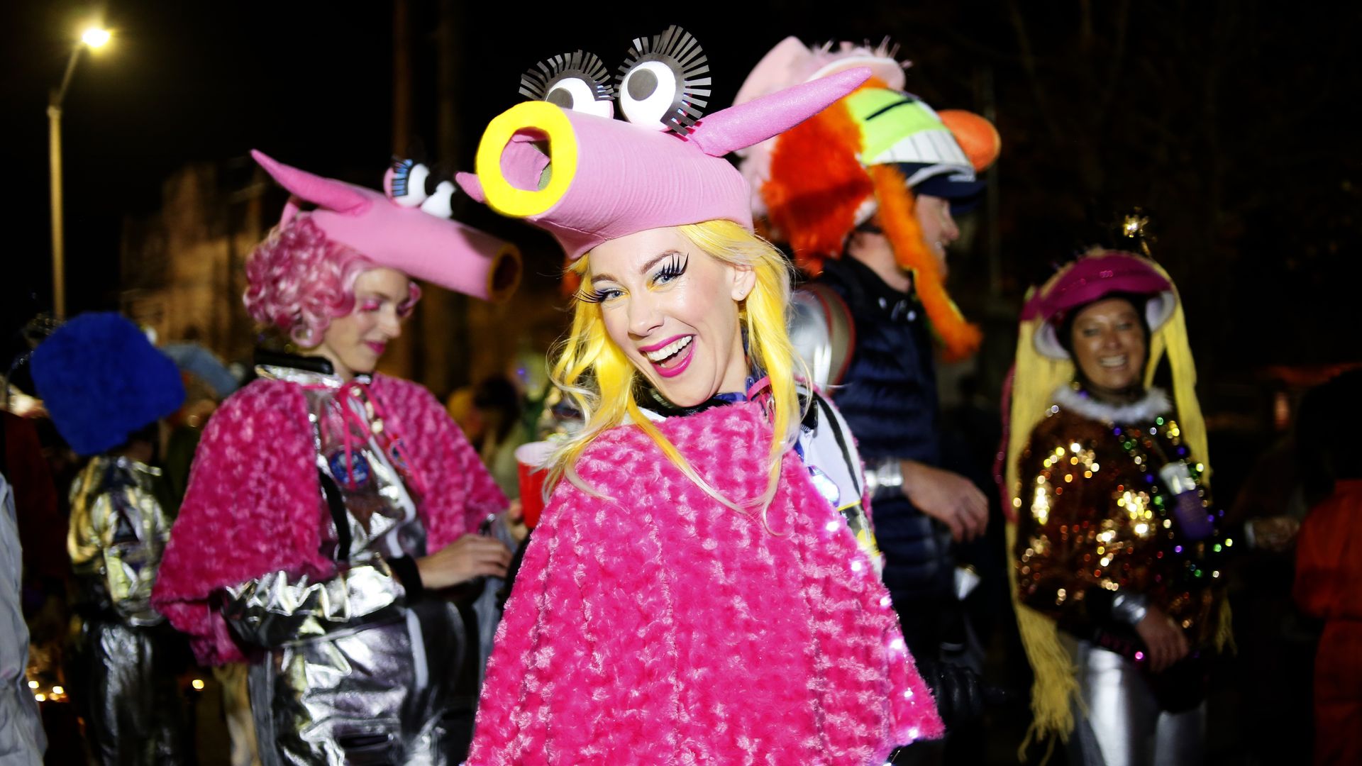 Photo shows a smiling woman with a pink costume on