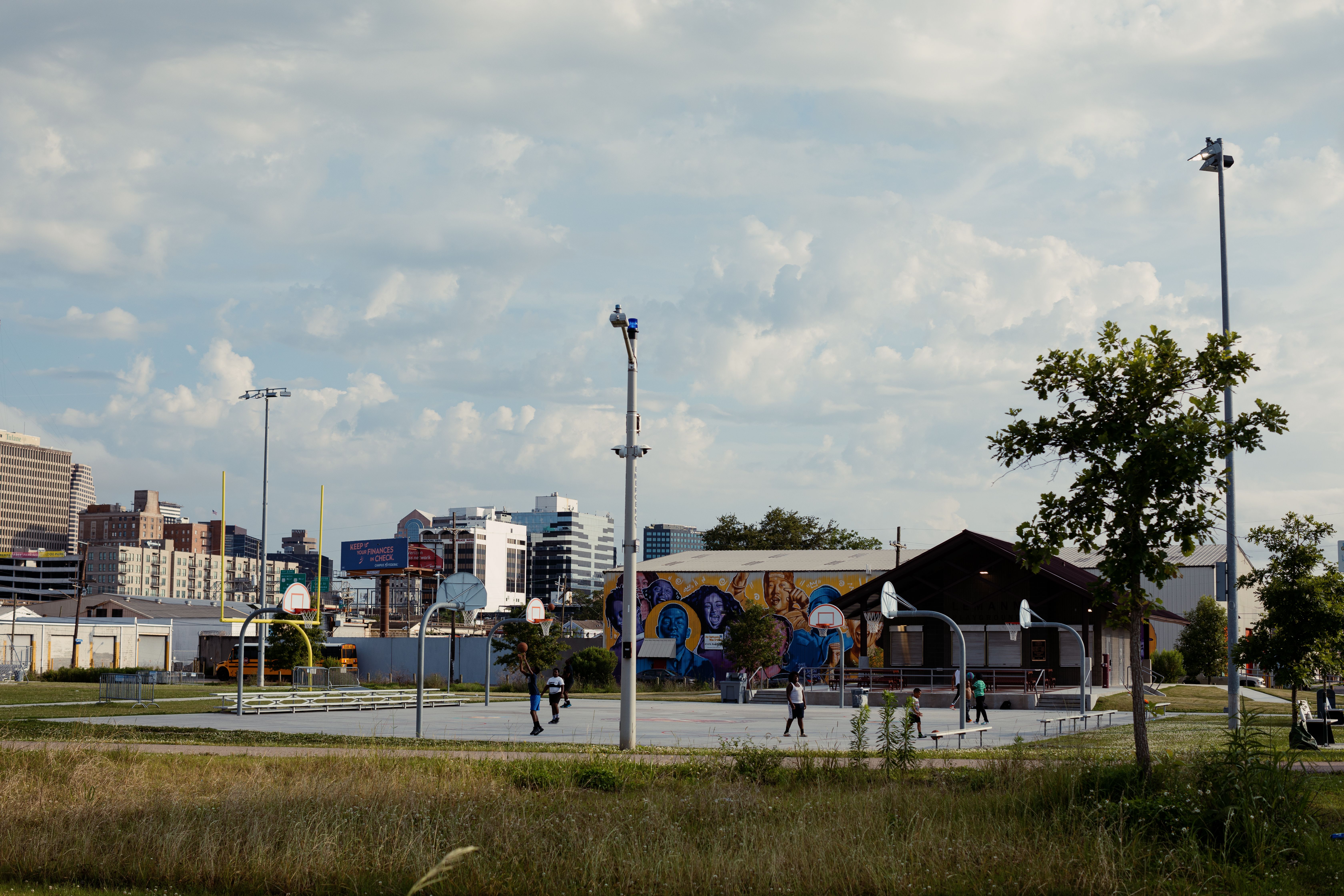A group of young people play basketball on a court viewed from afar.