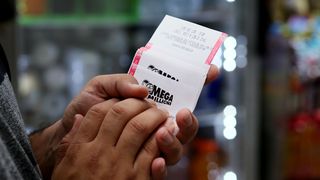 Hand holding mega millions lottery ticket
