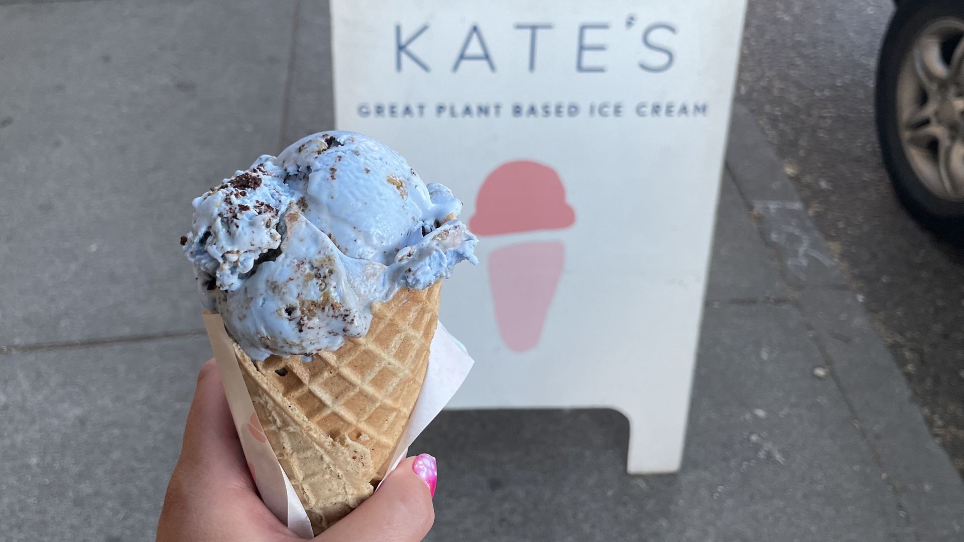 A photo of a hand holding an ice cream cone.