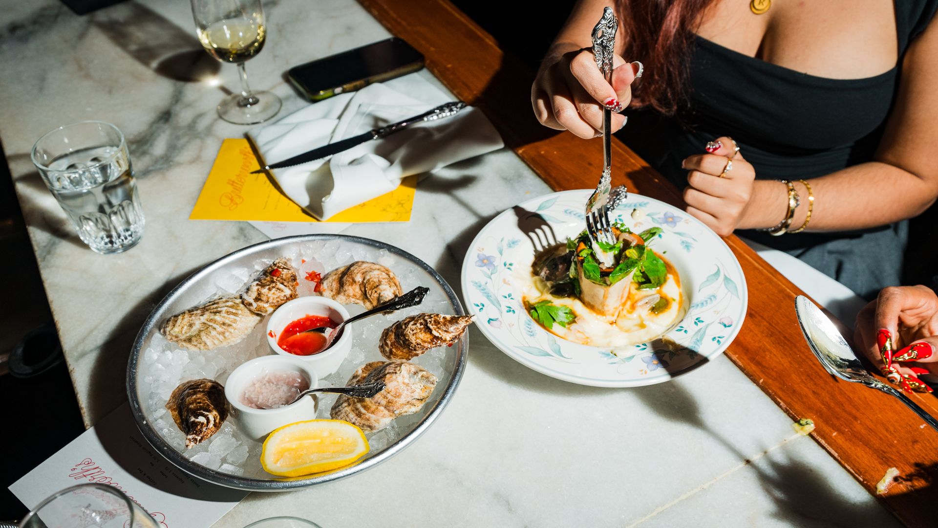 A woman digging into bone marrow at Butterworth's on Capitol Hill with oysters on the table