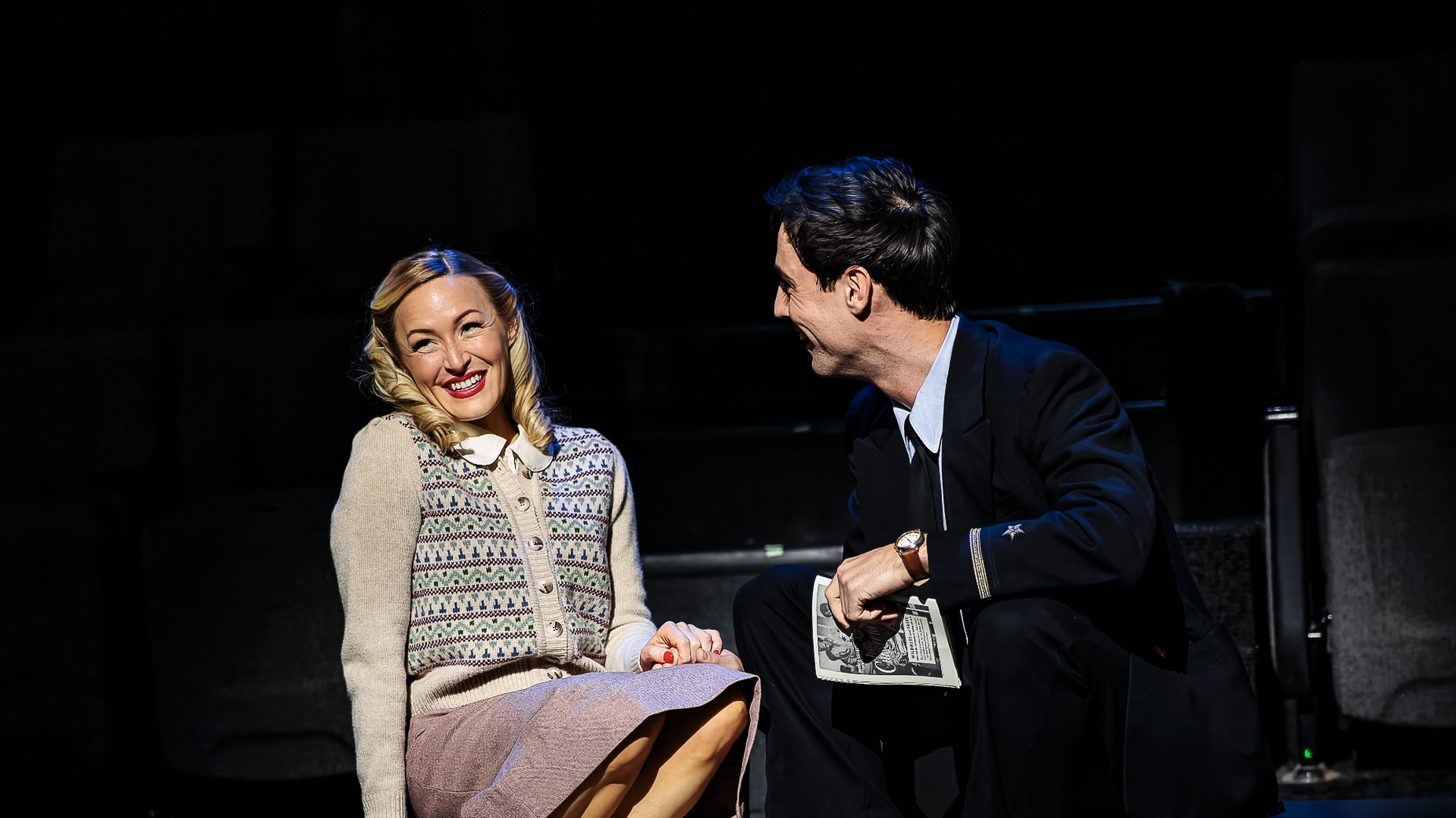 A photo of two people smiling on a stage.